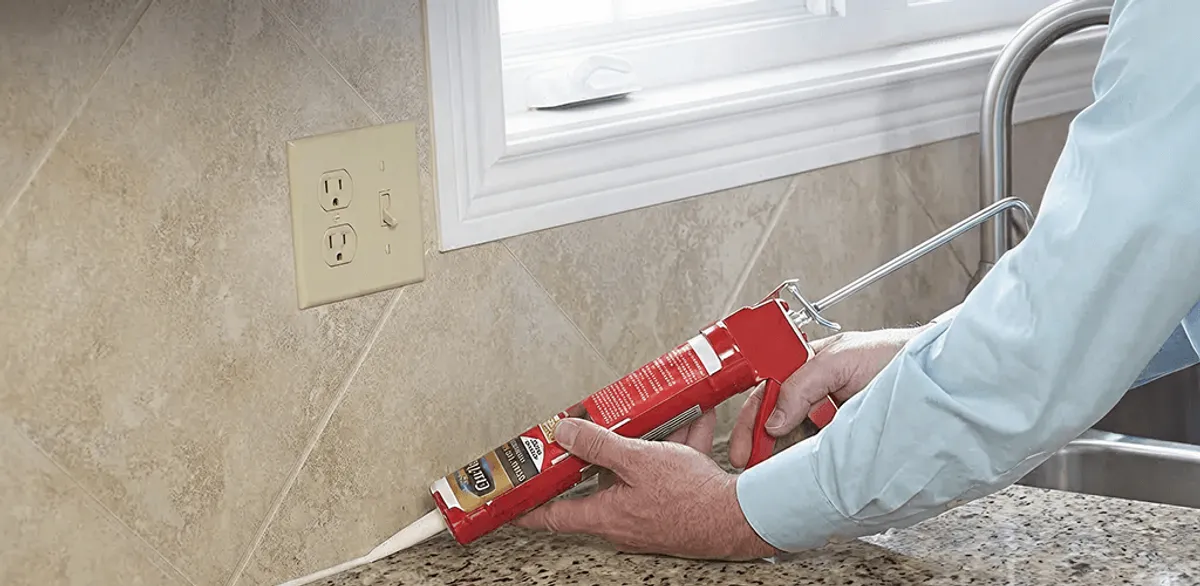 Handyman applying caulk along a kitchen backsplash and countertop seam in Cincinnati, OH