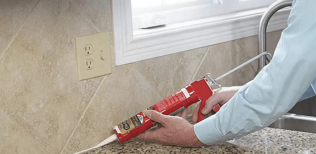 Handyman applying caulk along a kitchen backsplash and countertop seam in Cincinnati, OH