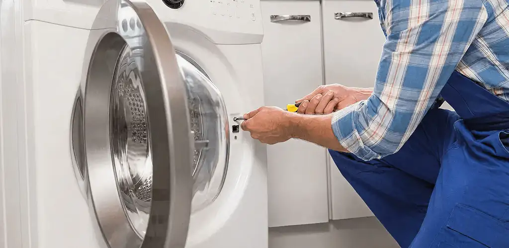 Handyman repairing a clothes dryer and checking electrical connections in Cincinnati, OH