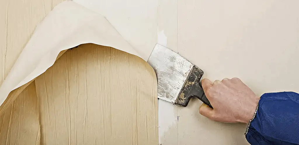 Handyman removing wallpaper with a scraper for wall preparation in Cincinnati, OH