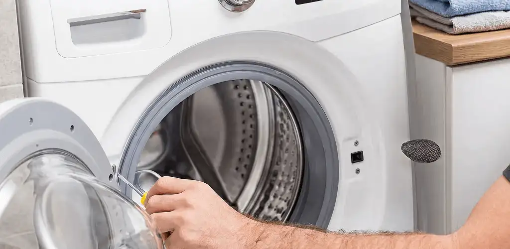 Handyman repairing a front-load washing machine and inspecting the drum in Cincinnati, OH