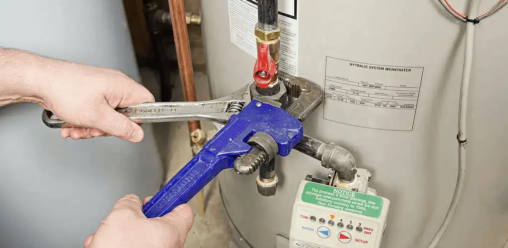 Water heater repair technician tightening the shutoff valve and supply line in Cincinnati, OH